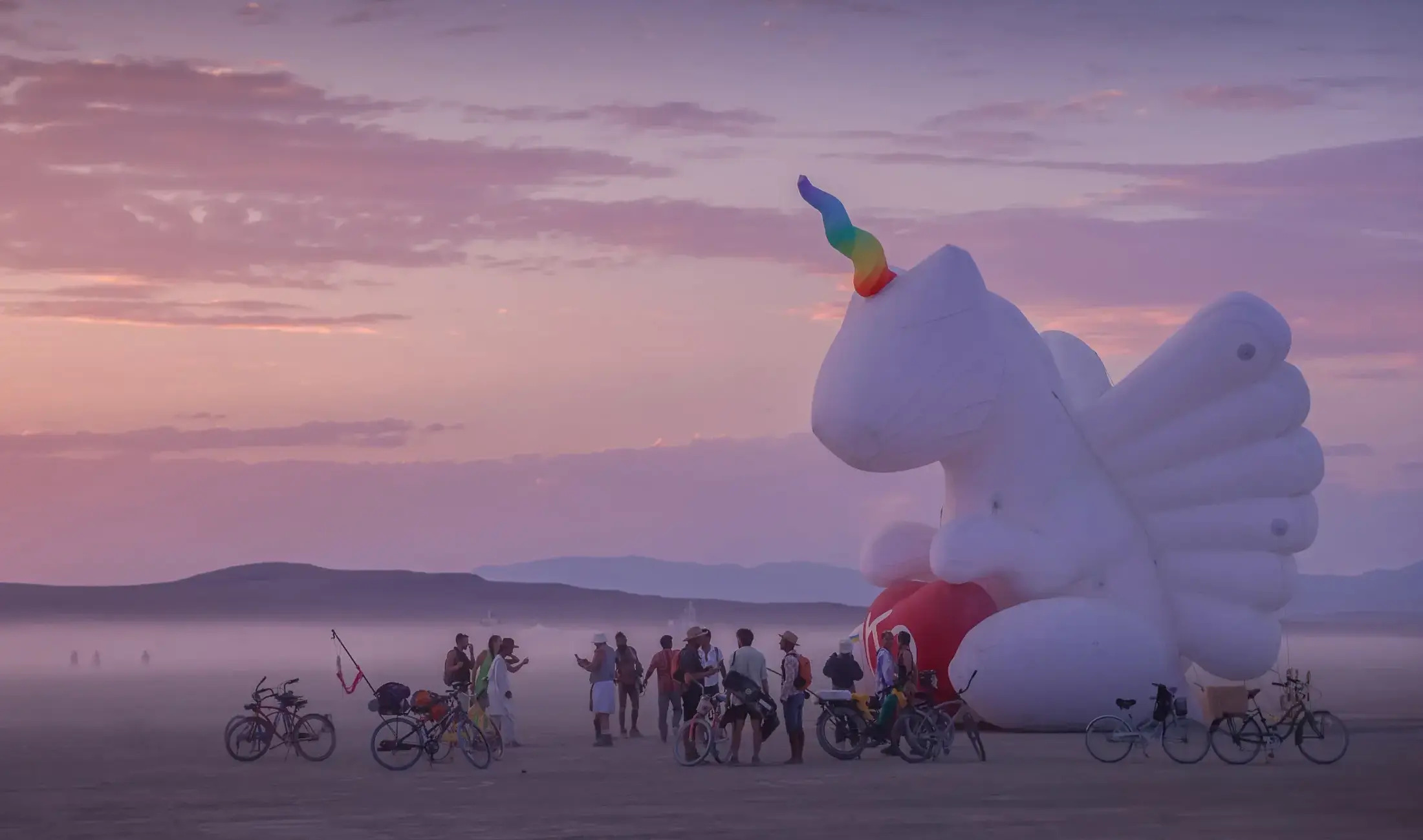 Burner vor einem aufblasbaren Kunstwerk in der Abenddämmerung während des Burning Man 2024